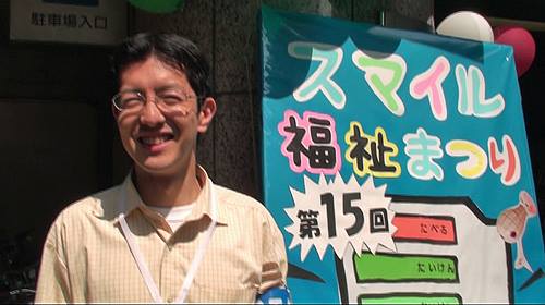 石坂わたるの活動:実行委員会事務局長として参加したスマイル福祉まつりの看板の前での写真